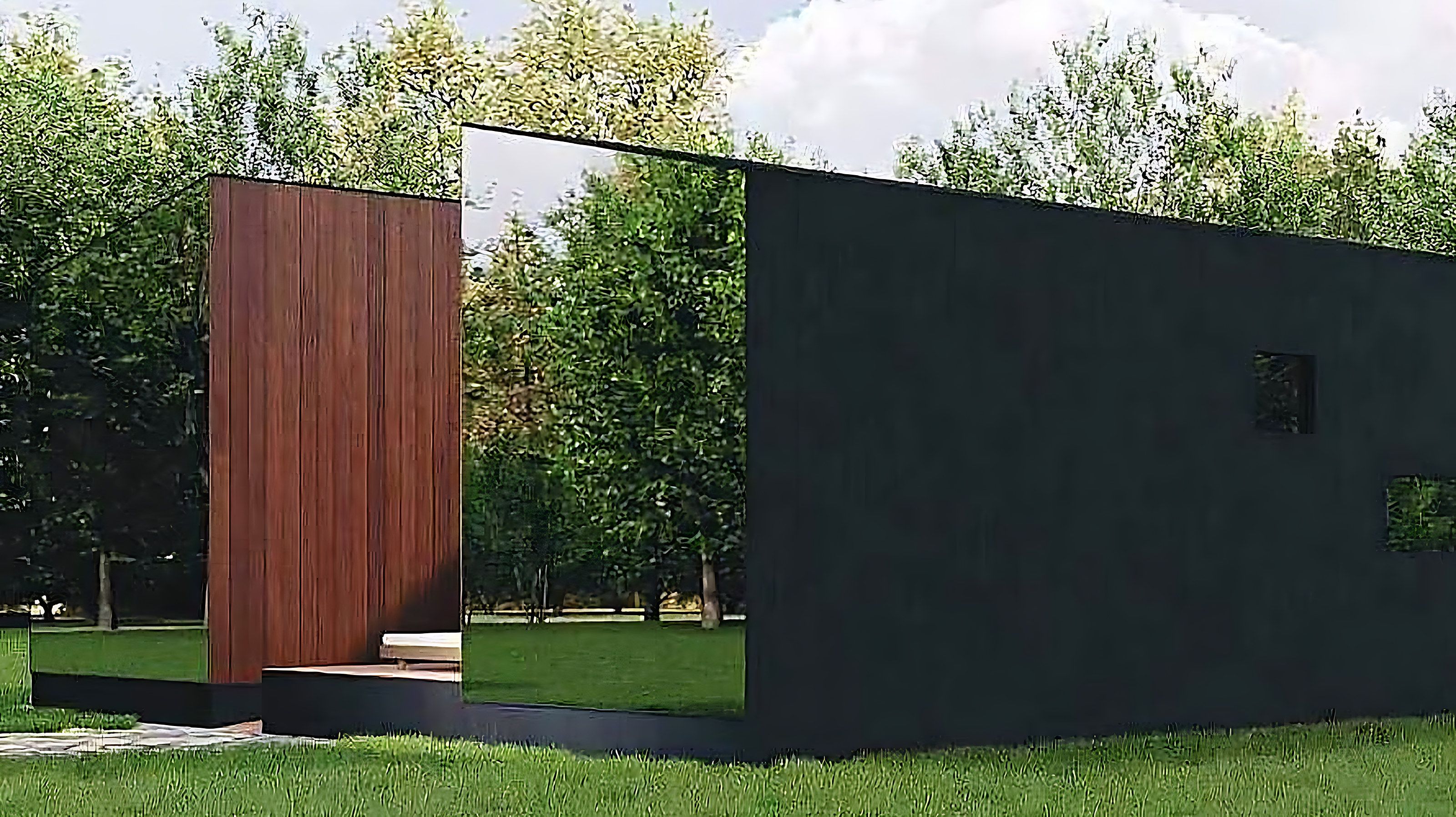 A cabin in charred timber and mirror glass in a green landscape